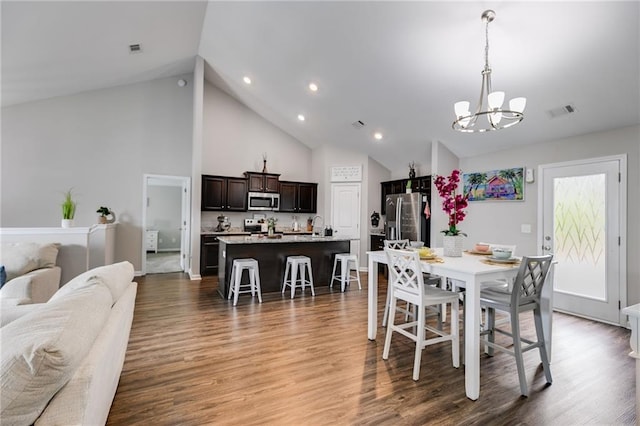 dining area with a chandelier, high vaulted ceiling, wood finished floors, recessed lighting, and baseboards