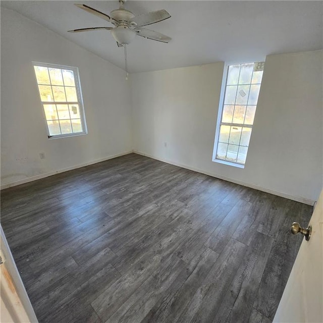 spare room with dark wood finished floors, vaulted ceiling, a ceiling fan, and baseboards