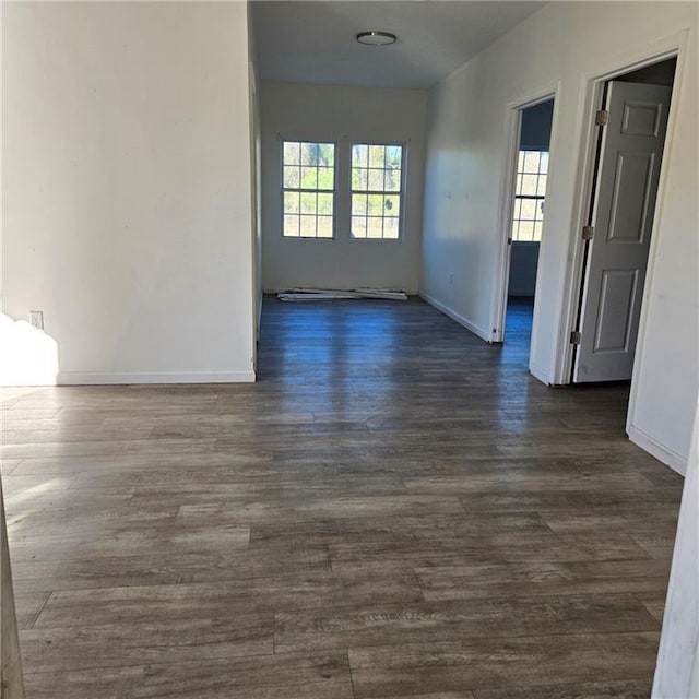 spare room featuring baseboards and dark wood-style flooring