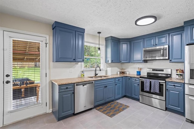 110 Village Ct, Woodstock, GA 30188 - kitchen featuring appliances with stainless steel finishes, blue cabinetry, light tile patterned flooring, pendant lighting, and light stone countertops