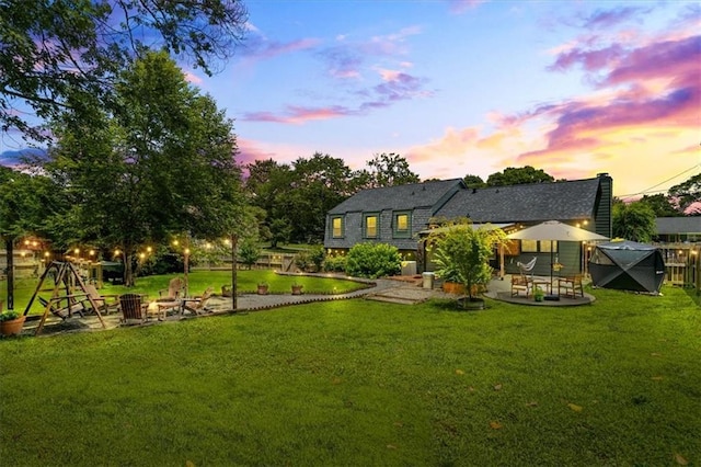 110 Village Ct, Woodstock, GA 30188 - back of house at dusk featuring a fire pit, a patio, and roof with shingles