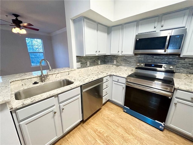 kitchen with crown molding, appliances with stainless steel finishes, kitchen peninsula, and sink