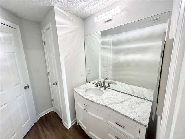 bathroom featuring hardwood / wood-style flooring, vanity, and a textured ceiling