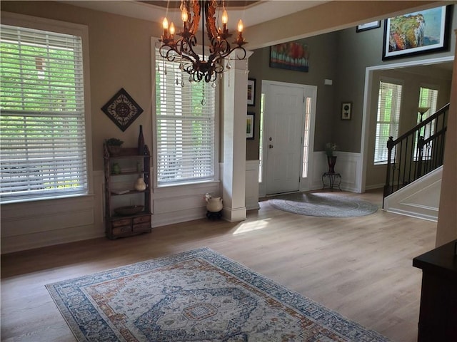 entryway featuring stairs, a notable chandelier, wainscoting, and wood finished floors