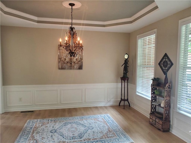 dining room featuring a tray ceiling, a chandelier, a healthy amount of sunlight, and light wood-style floors