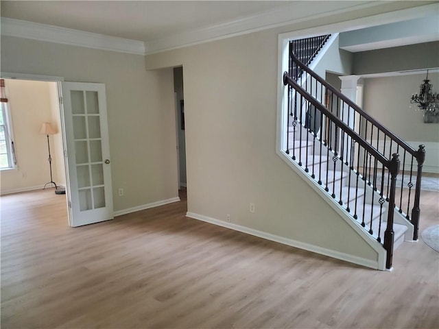 unfurnished living room featuring crown molding, wood finished floors, baseboards, and stairs