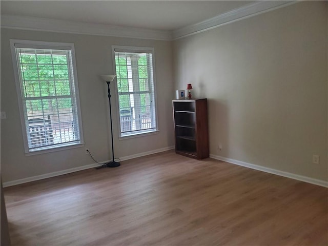 spare room featuring baseboards, light wood finished floors, and crown molding