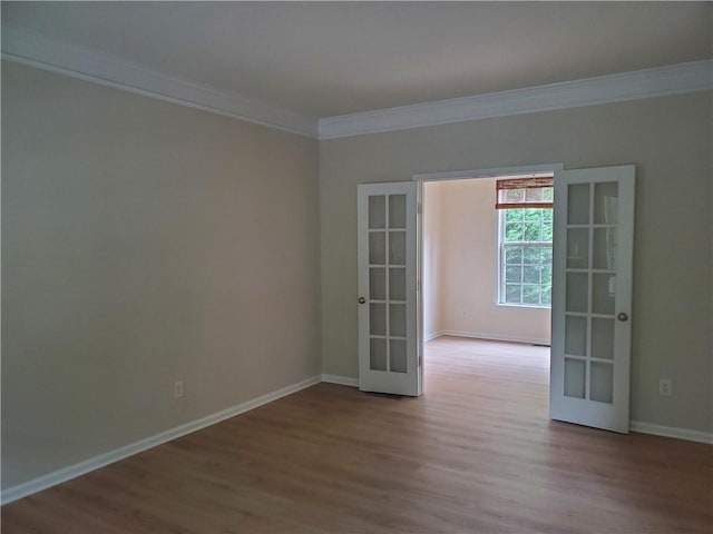 empty room featuring baseboards, french doors, crown molding, and wood finished floors