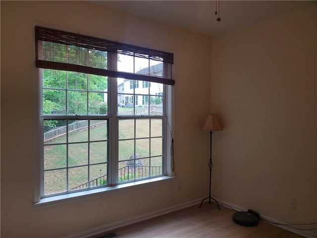 spare room featuring baseboards, light wood-style floors, and plenty of natural light
