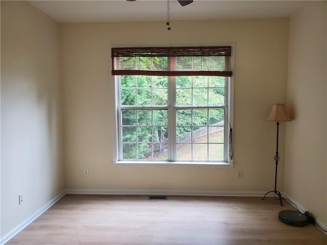 empty room with a ceiling fan, baseboards, light wood-type flooring, and visible vents