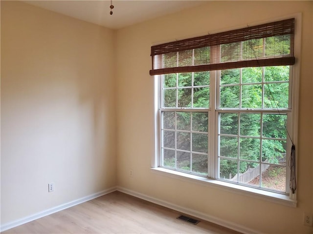 empty room featuring light wood-type flooring, visible vents, and baseboards