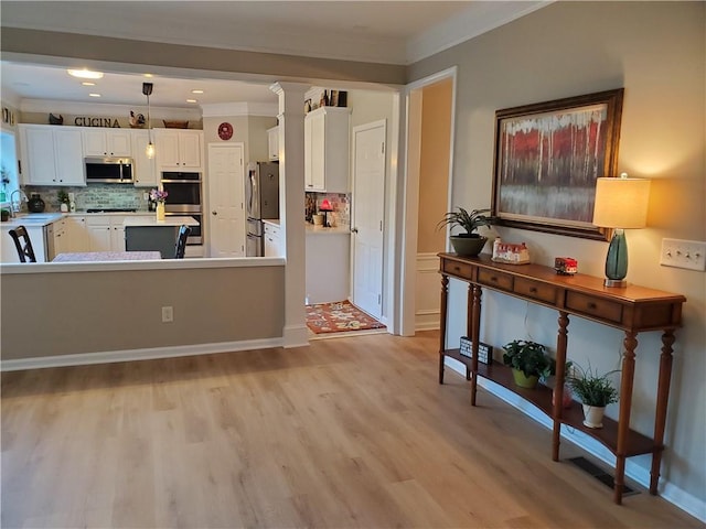 living area with recessed lighting, light wood-style flooring, crown molding, and decorative columns