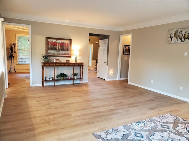 unfurnished living room with baseboards, light wood-type flooring, and crown molding