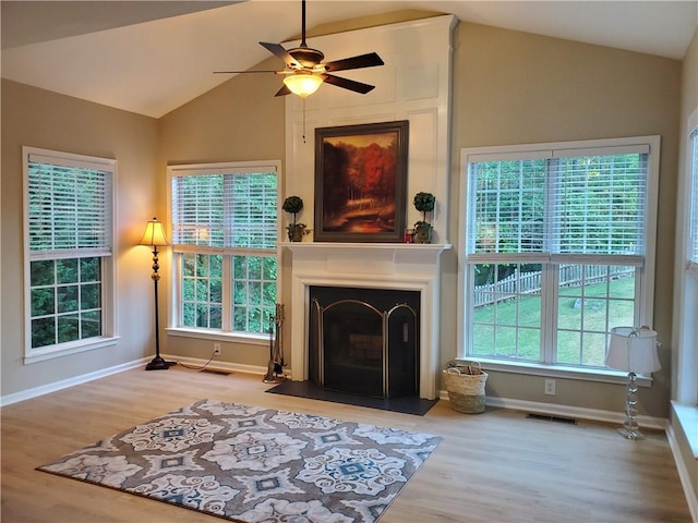 living room featuring a ceiling fan, wood finished floors, visible vents, and vaulted ceiling