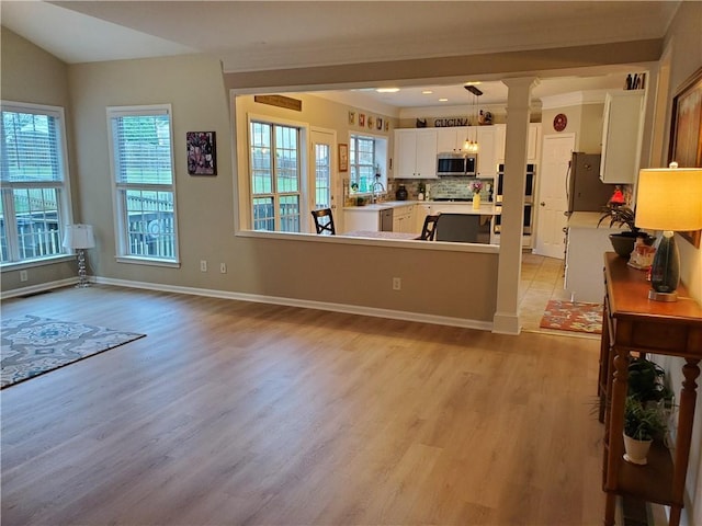 living area featuring light wood-type flooring, baseboards, and ornate columns