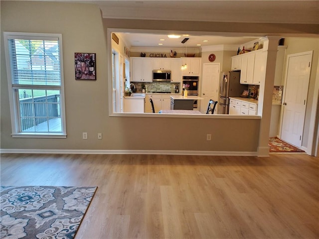 kitchen with white cabinetry, crown molding, backsplash, light wood-style floors, and stainless steel appliances