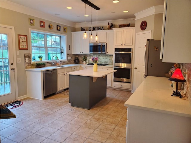 kitchen with a sink, stainless steel appliances, backsplash, a kitchen island, and ornamental molding