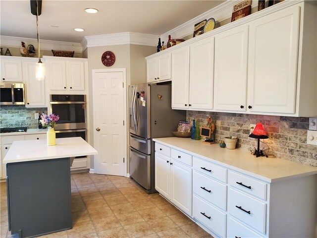 kitchen featuring light countertops, ornamental molding, decorative backsplash, stainless steel appliances, and white cabinets