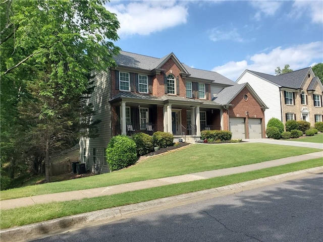 view of front of house featuring brick siding, covered porch, central AC, concrete driveway, and a front yard