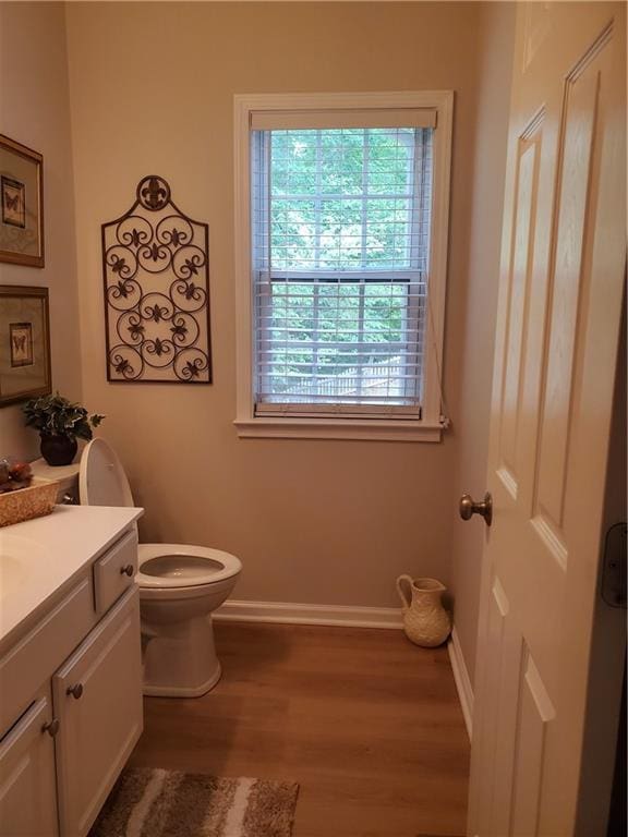 bathroom with wood finished floors, baseboards, vanity, and toilet