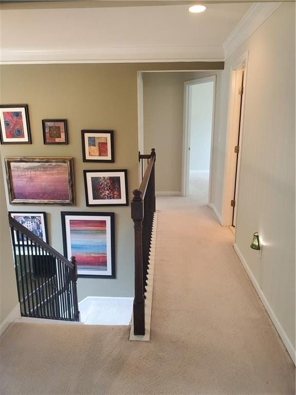 hallway featuring crown molding, carpet flooring, baseboards, and an upstairs landing