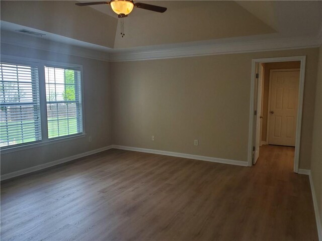 spare room with a ceiling fan, baseboards, ornamental molding, visible vents, and wood finished floors