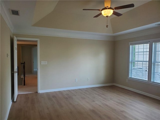 empty room featuring wood finished floors, visible vents, baseboards, ceiling fan, and ornamental molding