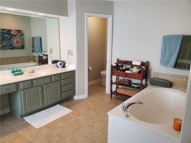 bathroom featuring toilet, baseboards, tile patterned floors, a garden tub, and vanity