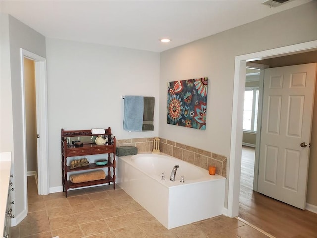full bathroom with tile patterned flooring, a garden tub, and baseboards