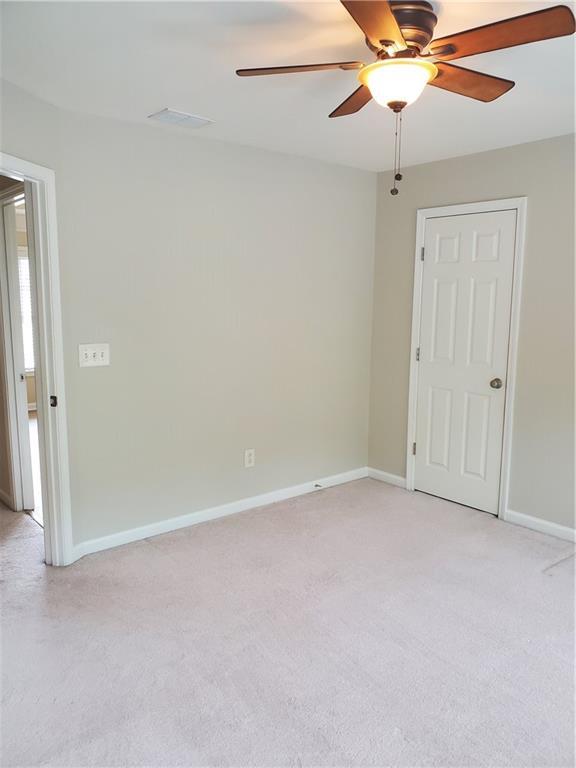 unfurnished room featuring light colored carpet, baseboards, and ceiling fan
