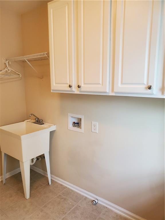 washroom featuring cabinet space, baseboards, a sink, and hookup for a washing machine