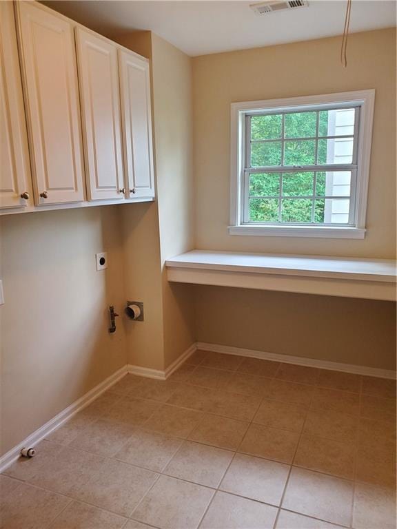 clothes washing area with light tile patterned floors, electric dryer hookup, cabinet space, visible vents, and baseboards