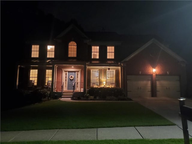 view of front of property featuring a lawn, a porch, driveway, and a garage