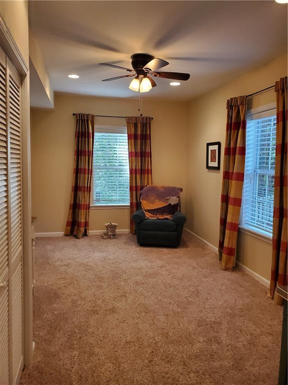 sitting room featuring a ceiling fan, baseboards, and carpet