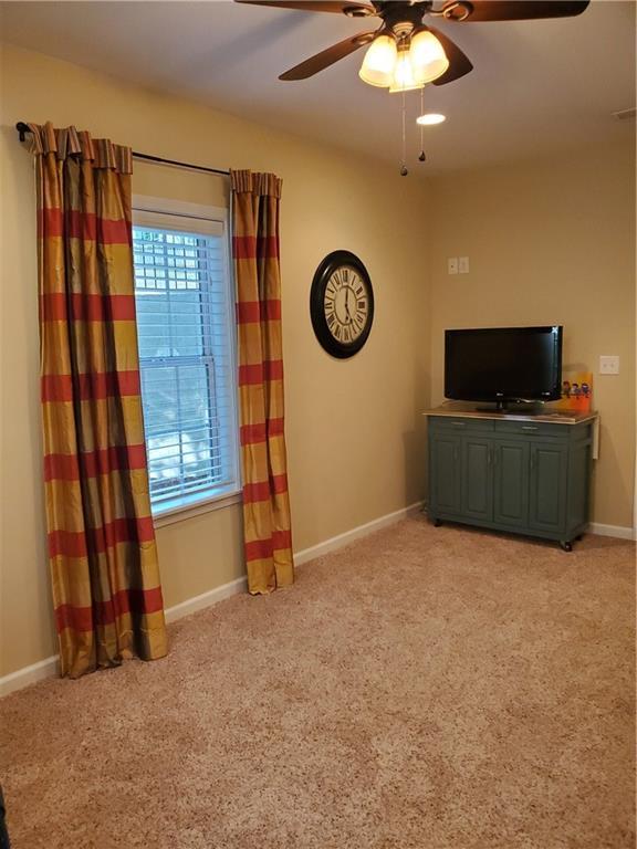 unfurnished living room with baseboards, light carpet, and ceiling fan