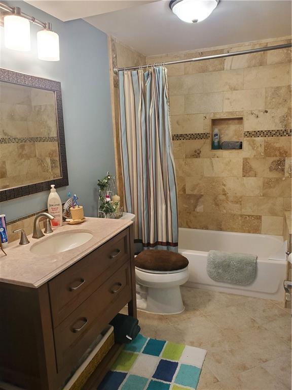 bathroom featuring shower / bath combination with curtain, toilet, and vanity