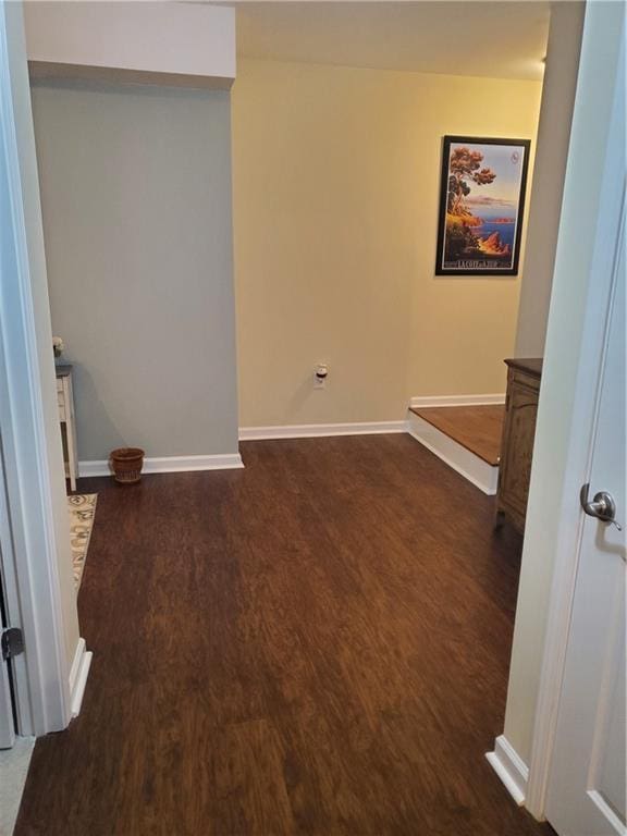 empty room featuring baseboards and dark wood finished floors