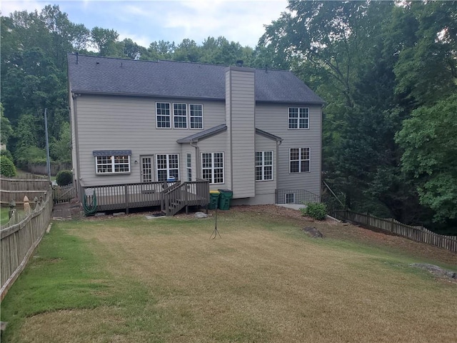 back of house with a chimney, a deck, a lawn, and a fenced backyard