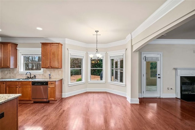 kitchen featuring crown molding, decorative light fixtures, stainless steel dishwasher, a fireplace, and decorative backsplash