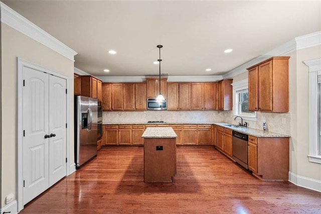 kitchen featuring light stone countertops, decorative light fixtures, stainless steel appliances, and a center island