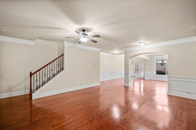 unfurnished living room with crown molding, ceiling fan with notable chandelier, and wood-type flooring