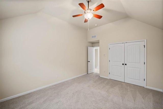 unfurnished bedroom featuring lofted ceiling, light carpet, ceiling fan, and a closet