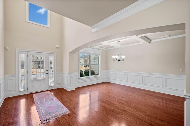 entryway with beamed ceiling, wood-type flooring, coffered ceiling, and an inviting chandelier