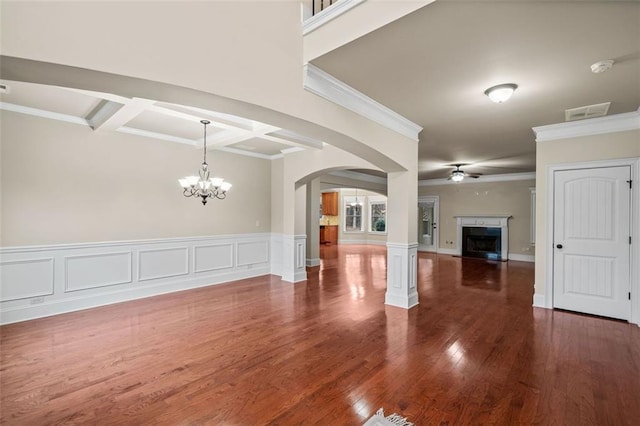 unfurnished living room with dark hardwood / wood-style flooring, ceiling fan with notable chandelier, and ornamental molding