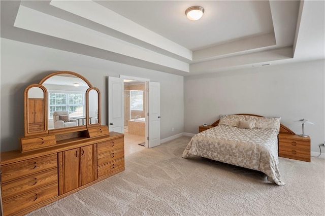 carpeted bedroom featuring connected bathroom and a tray ceiling