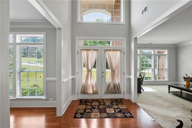 foyer featuring crown molding, carpet flooring, and french doors