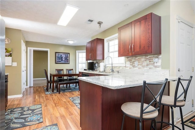 3090 Perch Ln SW, Marietta, GA 30008 - kitchen with a sink, light wood-style flooring, a peninsula, tasteful backsplash, and a breakfast bar area