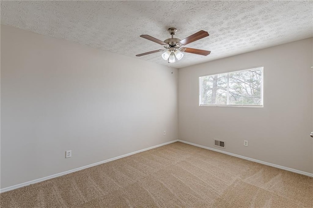 unfurnished room with ceiling fan, light colored carpet, and a textured ceiling