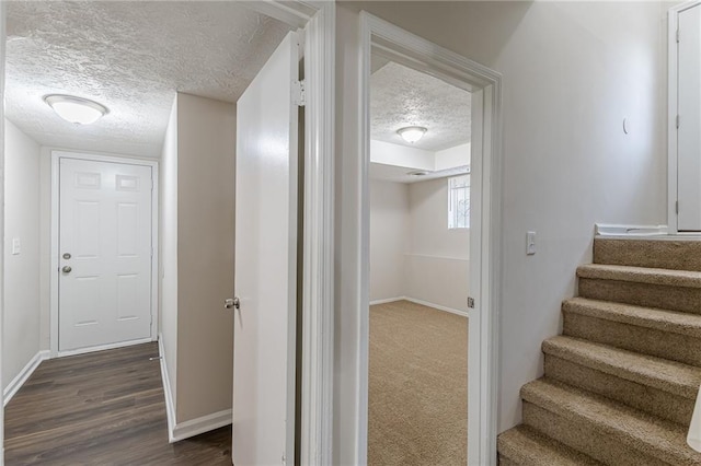 staircase with hardwood / wood-style floors and a textured ceiling