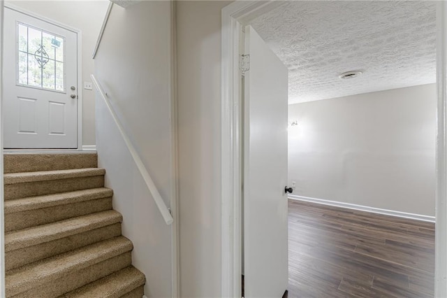 stairway featuring hardwood / wood-style flooring and a textured ceiling